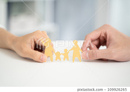 Hands of a couple working together and holding a paper cutout of their family 109926265