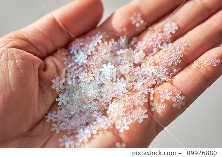 Sequins in the shape of snowflakes on the hand. Sequins in the shape of snowflakes on the hand. 109926880