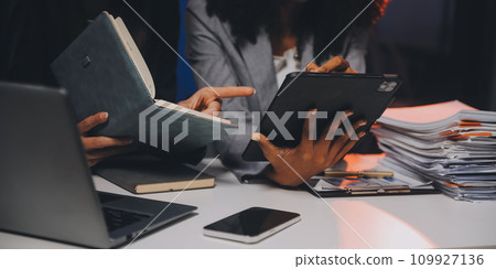 Team of software developers working on big project late at night in neon light trying to finish before deadline 109927136