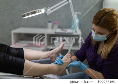 The beautician massages the client's feet after the scrub is completed. The beautician massages the client's feet after the scrub is completed. 109927460