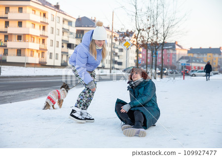 A passerby with a dog tries to help a woman get up. A passerby with a dog tries to help a woman get up. 109927477