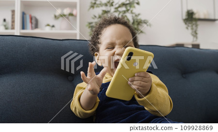 Extremely happy African American baby playing with parent's smartphone, childhood Extremely happy African American baby playing with parent's smartphone, childhood 109928869