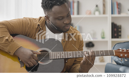 African American man learning to play guitar, musician rehearsing new single 109928872