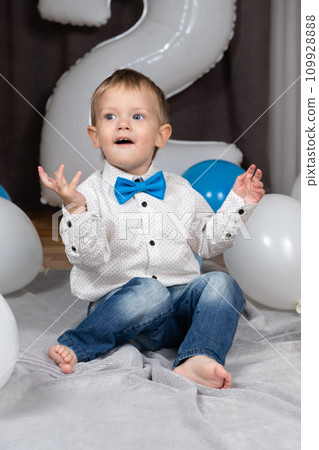 A little blond boy with blue eyes celebrates his birthday among inflatable balloons. 109928888