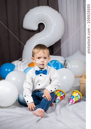 A little blond boy with blue eyes celebrates his birthday among inflatable balloons. 109928889