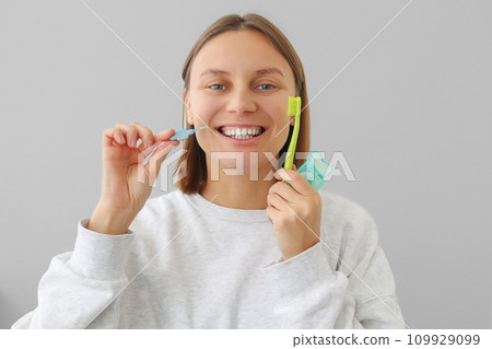 woman with white teeth holds dental floss, toothbrush and interdental brush to for prevent oral disease. Health care dentistry and oral hygiene concept. Daily routines caries prevention 109929099