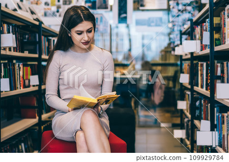 Stylish lady reading near bookcases 109929784