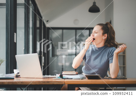 Bored businesswoman yawning at workplace feeling no motivation or lack of sleep tired of boring office routine. 109932411