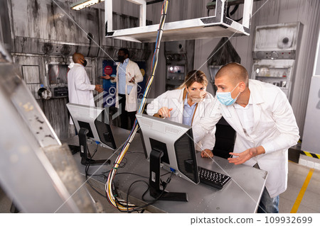 Friends in protective masks trying to solve conundrum in quest room in view as abandoned lab 109932699