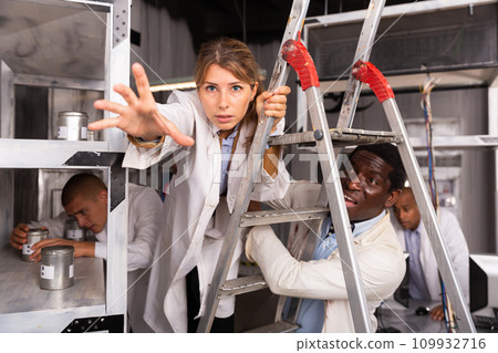 Girl on ladder in quest room with other multiracial people 109932716