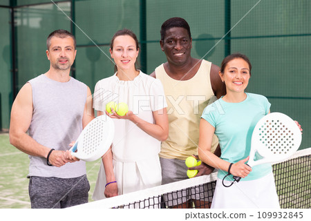 Four paddle tennis players posing on court Four paddle tennis players posing on court 109932845