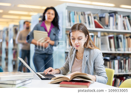 Girl student, studying on a laptop in the library Girl student, studying on a laptop in the library 109933005