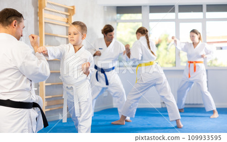 Boy is paired with man teacher to learn how to strike and rehearses blocking opponent Boy is paired with man teacher to learn how to strike and rehearses blocking opponent 109933595