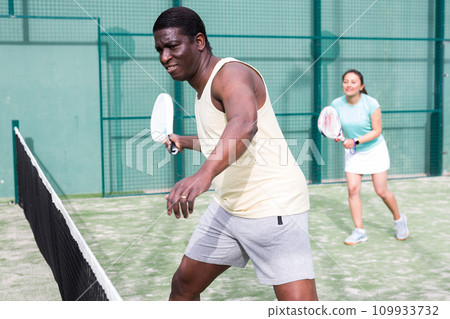 African american man and latino woman playing paddle tennis African american man and latino woman playing paddle tennis 109933732