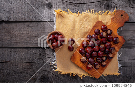 Chestnut in Wooden Plate and on Wooden Kitchen Board on Wooden Background. 109934846