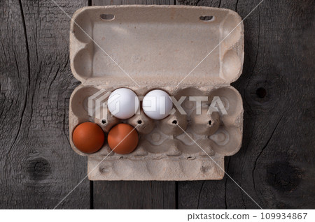 Raw Chicken Eggs in Egg Box on Wooden Background. 109934867