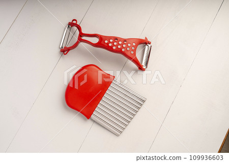 vegetable peeler and vegetable cutter on a wooden table in the kitchen close-up, a knife for cutting vegetables. The concept of home cooking. Selective Focus 109936603