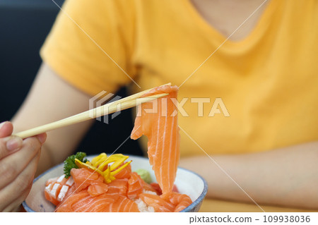 Asian woman eating salmon slice sashimi with rice in Japanese restaurant 109938036