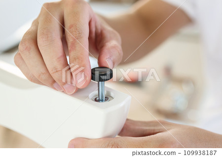 Asian man assembling furniture at home with adjustable table leg Asian man assembling furniture at home with adjustable table leg 109938187