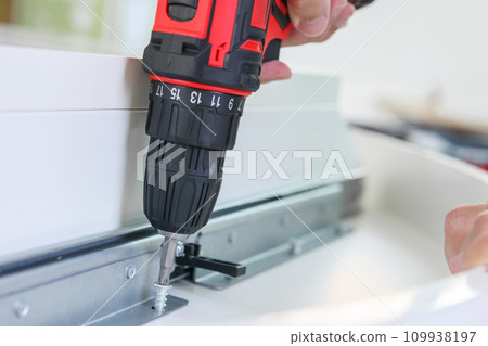 man assembling white table furniture at home using cordless screwdriver man assembling white table furniture at home using cordless screwdriver 109938197