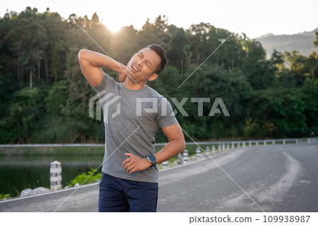 An Asian man in sportswear is feeling tired after a long run on a sunny day. An Asian man in sportswear is feeling tired after a long run on a sunny day. 109938987