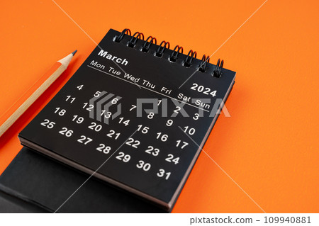 March 2024 desk calendar with pencil on orange background. 109940881