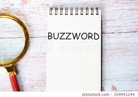 Buzzword a word written on a notebook on wooden boards next to a magnifying glass Buzzword a word written on a notebook on wooden boards next to a magnifying glass 109941244