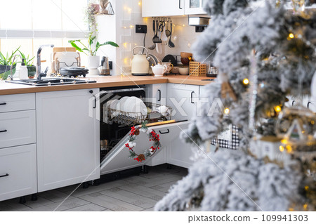 A lot of dirty dishes in the dishwasher in the festive kitchen. Helping the hostess, economy and ecology. Cleaning in the kitchen for the holidays of Christmas and New Year, after the feast and guests 109941303