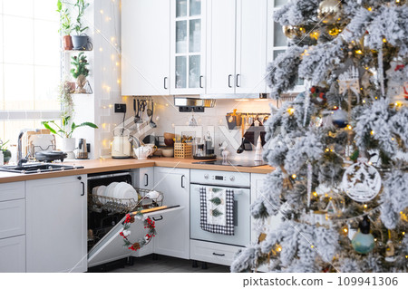 A lot of dirty dishes in the dishwasher in the festive kitchen. Helping the hostess, economy and ecology. Cleaning in the kitchen for the holidays of Christmas and New Year, after the feast and guests 109941306