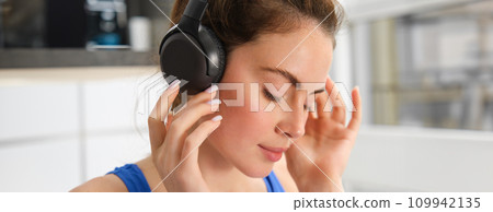 Face of beautiful woman in wireless headphones, enjoys sound, listens to music in wireless headphones 109942135