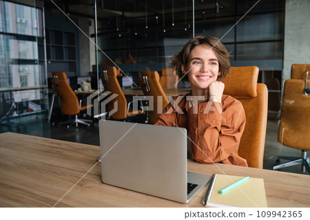 Image of girl at her workplace, digital nomad using laptop, sitting in an office, wearing casual clothes 109942365