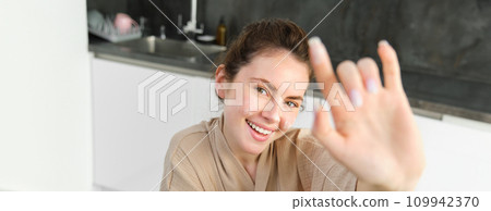 Attractive young cheerful girl baking at the kitchen, making dough, holding recipe book, having ideas 109942370