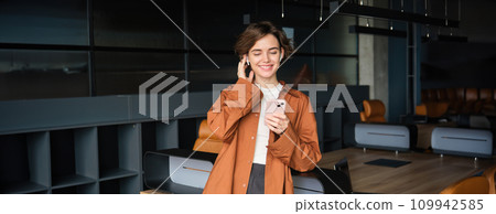 Image of office worker, employee working in conference room, talks on mobile phone with wireless headphones 109942585