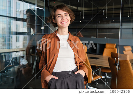 Portrait of young confident woman, start-up manager in office, posing with confidence, looking self-assured, wearing casual, informal clothes 109942596