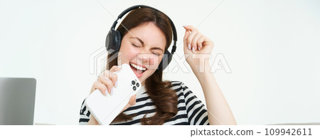 Carefree woman singing into smartphone microphone, playing mobile karaoke app, having fun, isolated on white background Carefree woman singing into smartphone microphone, playing mobile karaoke app, having fun, isolated on white background 109942611
