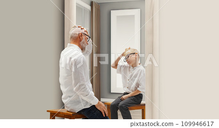 Years ago. Senior man sitting ear mirror with reflection of him as a child. Conceptual collage. Age, past and present, generation 109946617