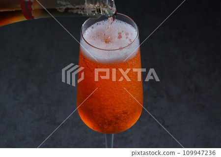 Pour well-chilled rosé champagne (sparkling wine) into a flute glass 109947236