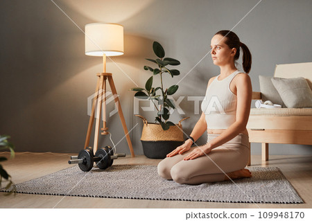 Fitness and yoga care. Indoor training for body. Beautiful female workout. Sporty beautiful woman sitting on the floor practicing yoga wear tip and leggings 109948170