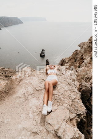 Woman travel sea. Young Happy woman posing on a beach over the sea on background of volcanic rocks, like in Iceland, sharing travel adventure journey 109948989