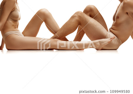 Cropped image of men's and women's bare legs against white studio background. Hair removal concept. Cropped image of men's and women's bare legs against white studio background. Hair removal concept. 109949580