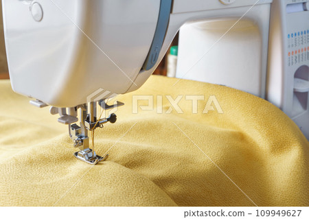 Modern sewing machine with yellow velours fabric close up Modern sewing machine with yellow velours fabric close up 109949627