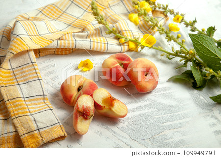 Halves and three whole saturn peaches or flat peach on white wooden background.. Halves and three whole saturn peaches or flat peach on white wooden background.. 109949791