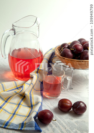 Plum Compote in jug with purple plums on white wooden background. . 109949799