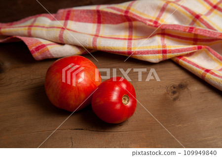 Red tomatoes and red towel on wooden background.. Red tomatoes and red towel on wooden background.. 109949840