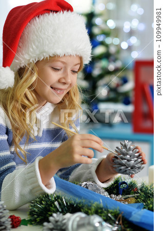 Happy girl in Santa hat sitting with Christmas present Happy girl in Santa hat sitting with Christmas present 109949981