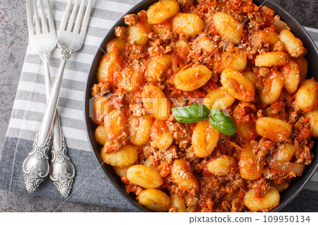 Hot Potato gnocchi with traditional Bolognese sauce and Parmesan cheese closeup on the plate. Horizontal top view 109950134