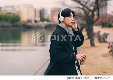 man listening to music by the river 109950876