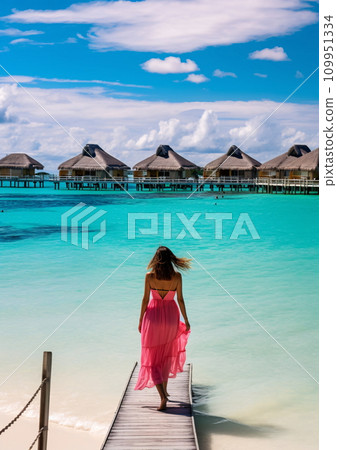 Woman in magenta red in front of ocean resort hut landscape, AI Generated 109951334