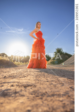 Elegant Woman in Vibrant Red Gown Against Sunset Sky Elegant Woman in Vibrant Red Gown Against Sunset Sky 109951901