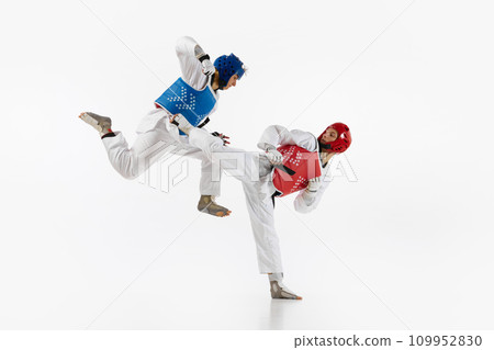 Dynamic image of young men, taekwondo athletes in kimono and helmets training isolated over white background. Martial arts, combat sport 109952830